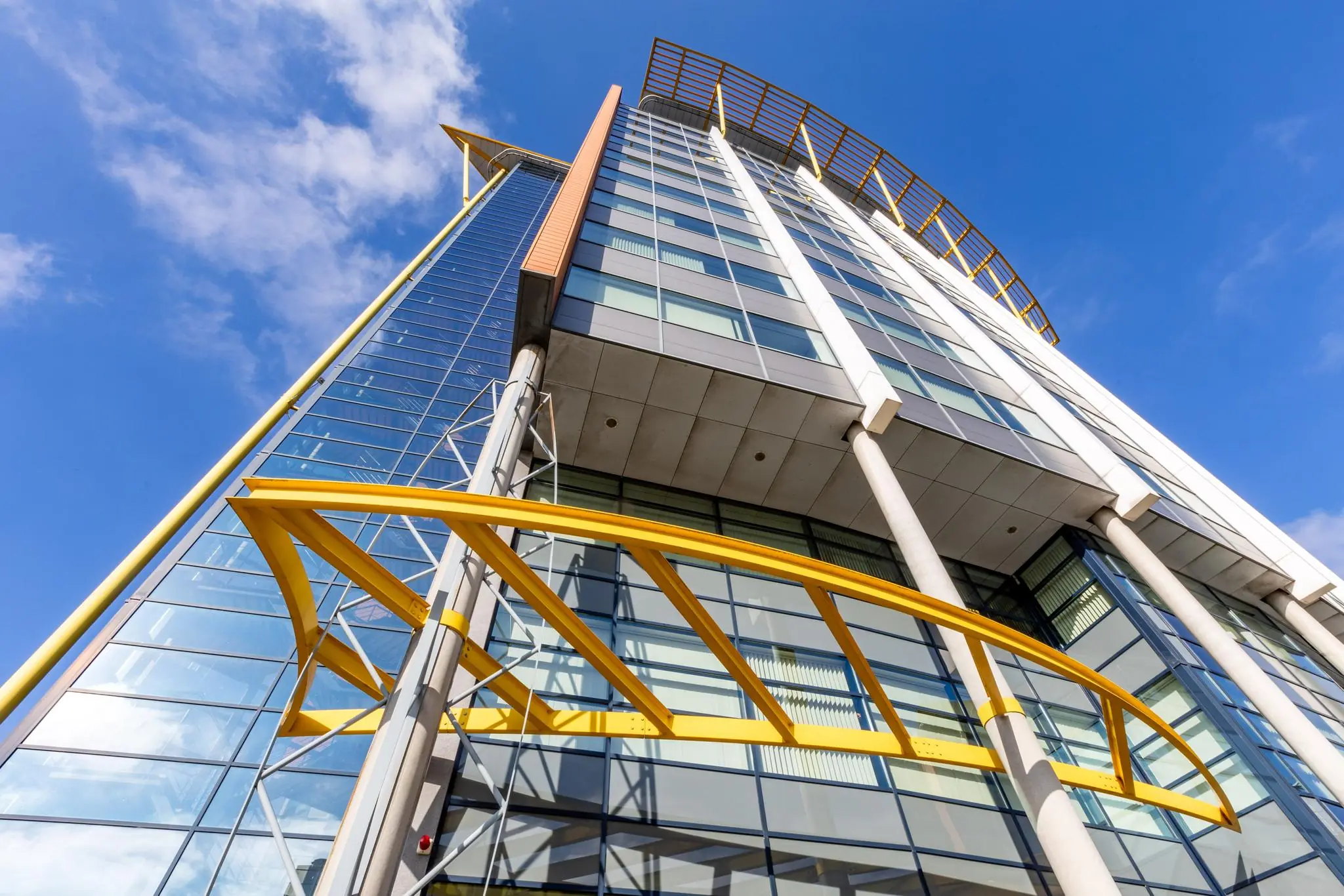 Hoog modern kantoorgebouw aan de Karel Doormanweg met opvallende gele accenten en glazen gevel, schuin van onderen gefotografeerd.